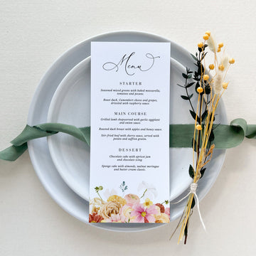 a table setting with a menu and flowers