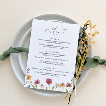 a white plate topped with a menu and flowers